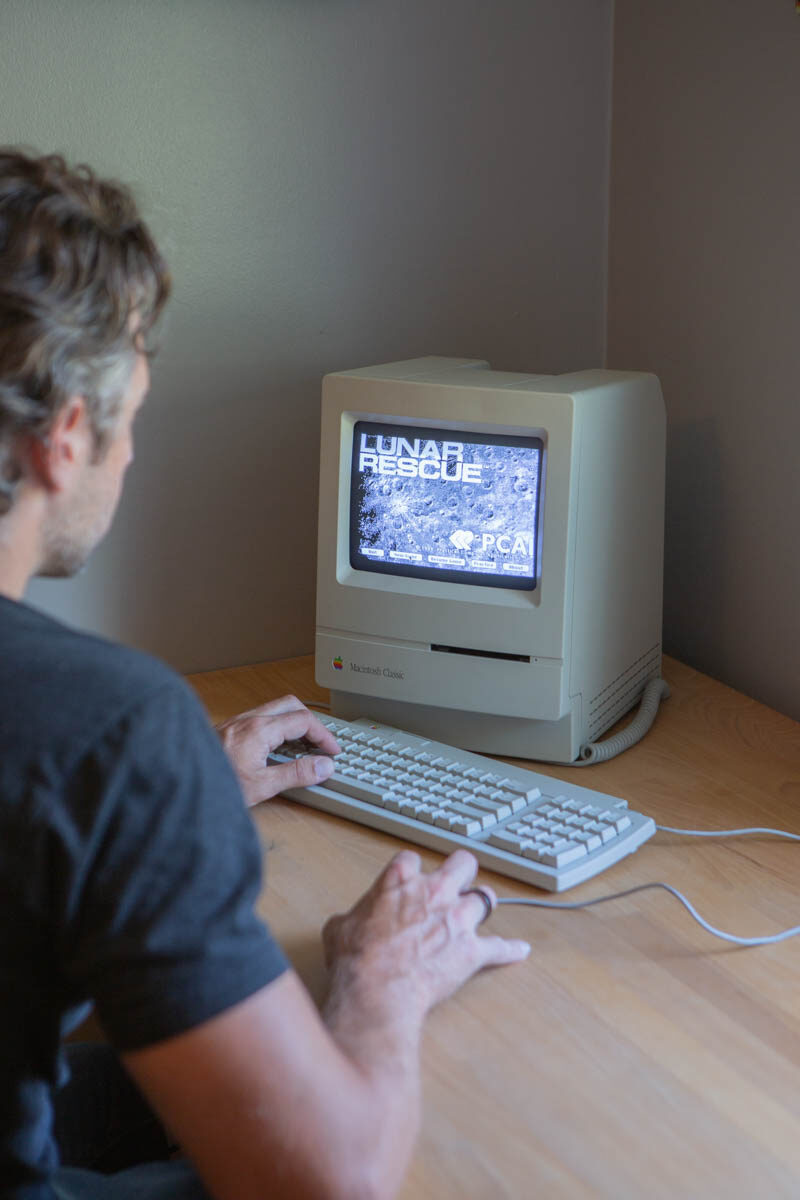 Playing a game on the restored Mac Classic, hands on the beige keyboard