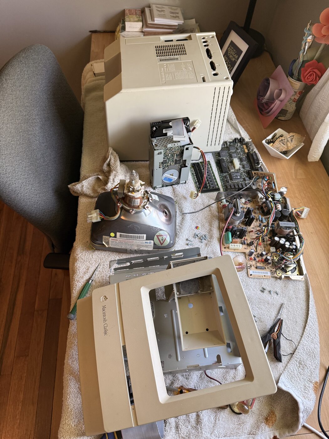The Macintosh Classic fully disassembled on a workbench — CRT, chassis, and boards laid out